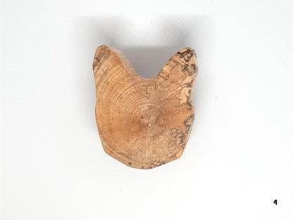 Paire de poignées en bois massif en forme de tête de chat, sculptées à partir de rondins de bois naturel avec leurs cernes visibles. Sur des portes blanches, elles apportent une touche artisanale et originale au mobilier. Fabrication artisanale