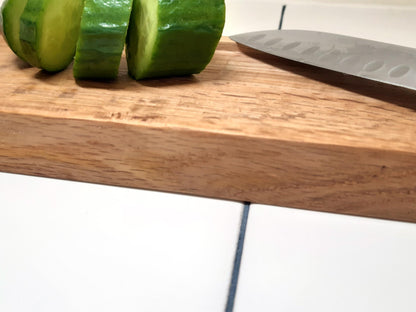 Planche à découper réversible en bois massif, avec côté classique et côté à rebords, inspiré de la recette de concombre de Lena Situations. Idéale pour découper légumes, saucisson ou pain avec précision. Accessoire de cuisine artisanal et design.