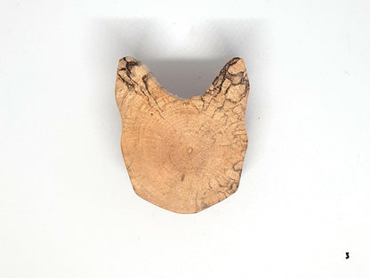 Paire de poignées en bois massif en forme de tête de chat, sculptées à partir de rondins de bois naturel avec leurs cernes visibles. Sur des portes blanches, elles apportent une touche artisanale et originale au mobilier. Fabrication artisanale