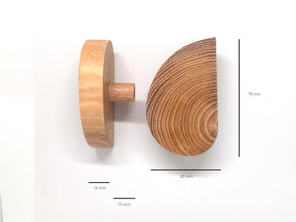 Vue rapprochée de deux poignées de placard en bois clair, en forme de demi-lune, montées sur des portes blanches. Leur position symétrique crée une esthétique circulaire harmonieuse une fois les portes fermées. Idéal pour une inspiration déco alliant simplicité, fonctionnalité et élégance naturelle. Parfait pour les recherches liées aux tendances de design d'intérieur en bois et aux poignées de meuble contemporaines.