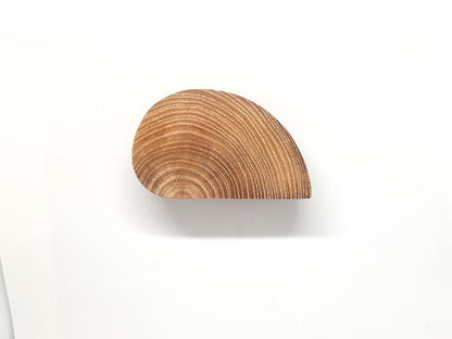 Poignées de meuble en bois en forme de demi-cercle fixées sur deux portes blanches adjacentes. L’effet visuel crée un cercle complet lorsqu’elles sont fermées. Design minimaliste et naturel, idéal pour une décoration intérieure scandinave ou moderne. Le bois brut met en valeur les veines naturelles pour un rendu chaleureux. Image parfaite pour illustrer des idées de poignées originales ou de meubles sur mesure.