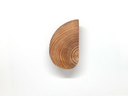 Image de deux poignées en bois naturel, sculptées en demi-cercles et installées sur des portes blanches côte à côte. L’effet miroir entre les deux poignées crée un cercle complet, ajoutant une touche design et graphique à un meuble minimaliste. Cette photo illustre une tendance déco éco-responsable, idéale pour optimiser l’agencement d’espaces contemporains. Mot-clés : poignée bois, meuble design, décoration épurée.